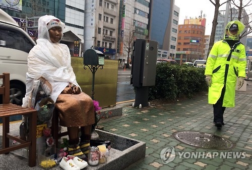 资料图片:2月20日上午,在釜山日领馆前,一名韩国警察走过慰安妇少女铜像旁。(韩联社)