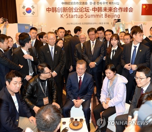 President Moon Jae-in (C) talks with Korean startup company officials while visiting a business forum hosted by the Korea Trade-Investment Promotion Agency (KOTRA) in Beijing on Dec. 14, 2017, in this photo provided by the agency. (Yonhap)