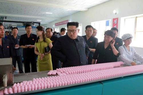 North Korean leader Kim Jong-un (C) visits a cosmetics factory in Sinuiju with his wife, Lee Sol-ju (4th from L), according to Korean Central News Agency reports on July 1, 2018. (For Use Only in the Republic of Korea. No Redistribution.) (Yonhap)