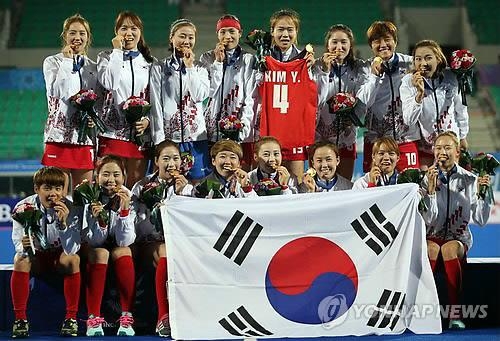 In this file photo from Oct. 1, 2014, South Korean women's field hockey players celebrate their gold medal at the 2014 Asian Games at Seonhak Hockey Stadium in Incheon, 40 kilometers west of Seoul, with one player holding up the No. 4 uniform of Kim Young-ran, who missed the competition with a knee injury. (Yonhap)