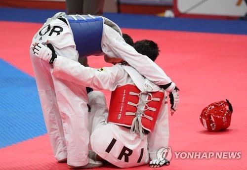 South Korea's Lee Dae-hoon (L) consoles Iran's Amirmohammad Bakhshikalhori after the men's taekwondo 68-kilogram division sparring competition final at the 18th Asian Games at Jakarta Convention Center in Jakarta on Aug. 23, 2018. (Yonhap)