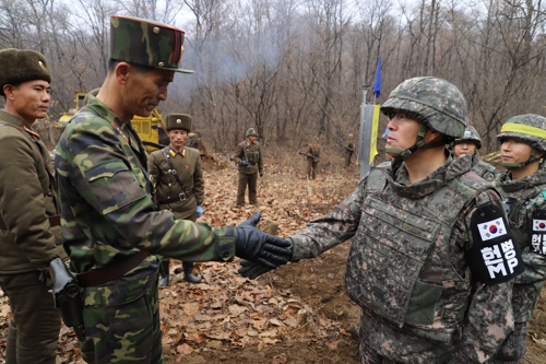 This photo, provided by South Korea's defense ministry, shows a South Korean official shaking hands with his North Korean counterpart during a recent operation near the Military Demarcation Line to construct a tactical road to support a joint project to excavate Korean War remains in the Demilitarized Zone. (Yonhap)