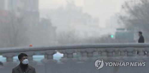 A man walks along the Cheonggyecheon Stream in downtown Seoul on Jan. 14, 2019, with the sky thick with fine dust. (Yonhap)