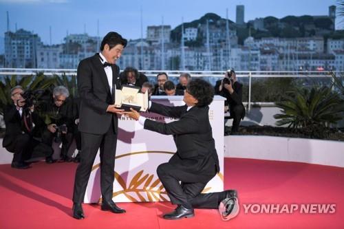 This photo provided by the AFP shows South Korean director Bong Joon-ho (R) and actor Song Kang-ho posing with the trophy during a photo-call after winning the Palme d'Or for "Parasite" at the closing ceremony of the 72nd Cannes Film Festival on May 25, 2019. (Yonhap)