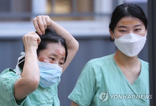 Medical staffers use band-aids to cover wounds on their faces caused by wearing protective goggles for long hours while treating coronavirus patients at Dongsan Hospital in Daegu, 300 kilometers southeast of Seoul, on March 4, 2020. (Yonhap)