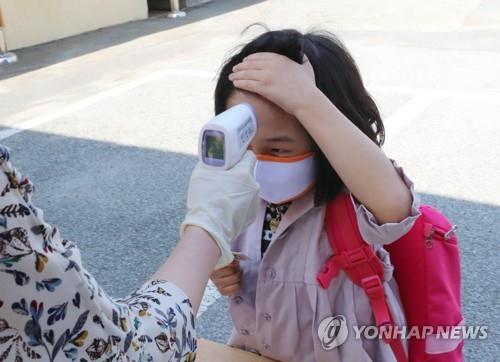 A pupil exposes her forehead to have her temperature checked at Ochi Elementary School in the southwestern city of Gwangju on May 29, 2020, amid the coronavirus pandemic. (Yonhap) 