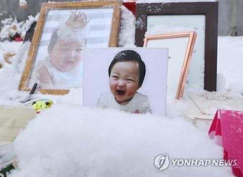 Photos of Jung-in are laid at the grave site where the child was buried in Yangpyeong, south of Seoul, on Jan. 13, 2021. (Yonhap)