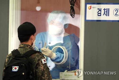 A service member undergoes a COVID-19 test at a temporary testing site in front of Seoul Station in central Seoul on April 5, 2021. (Yonhap) 