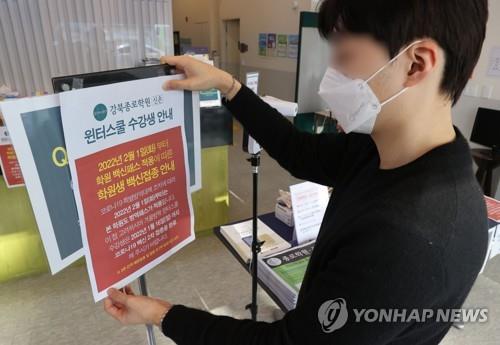 An employee posts a notice informing visitors of a new requirement for vaccine passes at a cram school in Seoul on Dec. 7, 2021. (Yonhap)