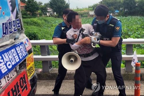 This photo captured from Facebook shows a protester being arrested by police on charges of threatening an aide to former President Moon Jae-in in front of Moon's home in Yangsan, 309 kilometers southeast of Seoul, on Aug. 16, 2022. (PHOTO NOT FOR SALE) (Yonhap)