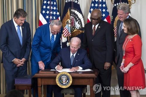 This EPA photo shows U.S. President Joe Biden, surrounded by Democratic lawmakers, signs the Inflation Reduction Act in the State Dining Room of the White House in Washington On Aug. 16, 2022. (PHOTO NOT FOR SALE) (Yonhap)