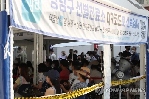 Des gens attendent dans un centre de dépistage à Gangnam, dans le sud de Séoul, pour se soumettre à un test de dépistage du nouveau coronavirus (Covid-19), le 30 juillet 2021.
