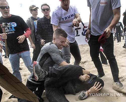 (로스앤젤레스 AP=연합뉴스) 미국 캘리포니아주 헌팅턴비치에서 지난달 25일(현지시간) 열린 도널드 트럼프 대통령 지지 집회에서 트럼프 대통령에 반대하는 한 남성이 이 집회 주최 여성요원 얼굴에 고추 스프레이를 뿌리고 달아나다 트럼프 지지자들에게 붙잡혀 집단 폭행을 당하고 있다.