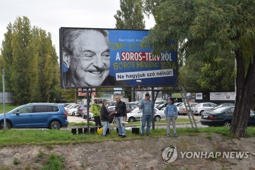 反소로스 캠페인 포스터 앞에 선 헝가리 NGO 활동가