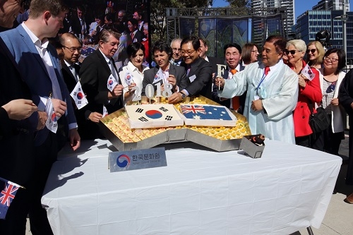 호주 시드니 한민족축제에서 양국 인사 한국과 호주 깃발을 떡케이크에 꼿고 있다.