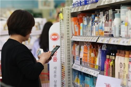 외국인 관광객이 선케어 제품을 휴대전화로 알아보고 있습니다.