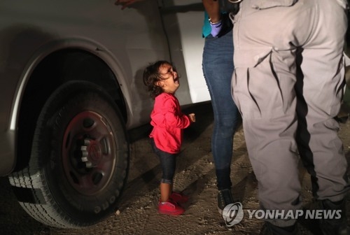 지난 12일(현지시간) 미국과 멕시코 국경에서 몸수색을 당하는 엄마 옆에서 울고 있는 온두라스 소녀 [John Moore/Getty Images/AFP=연합뉴스]