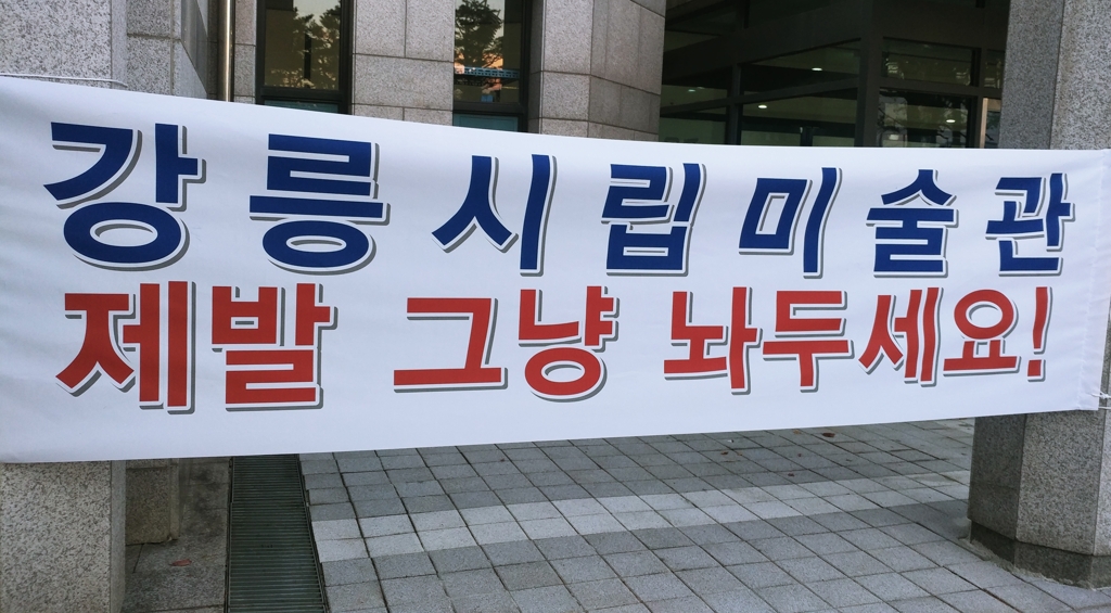 강릉시가 도심 재생사업을 추진하면서 강릉시선거관리위원회가 강릉시립미술관으로 이전하는 방안이 검토되자 미술인들이 반발하는 현수막을 내걸었다.