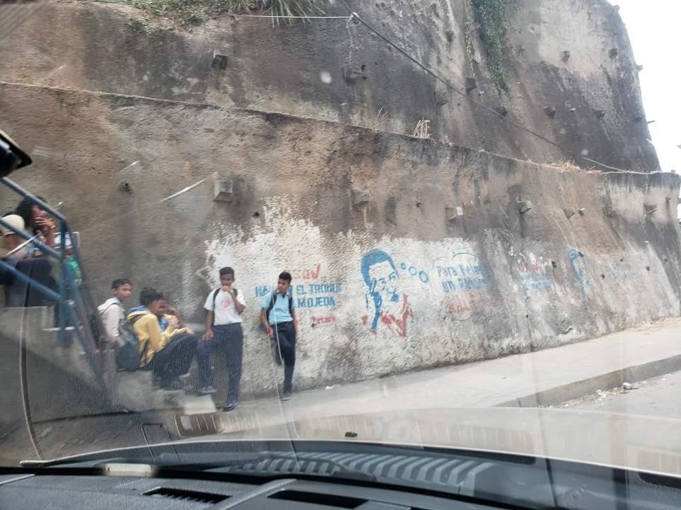우고 차베스 전 베네수엘라 대통령의 벽화가 그려진 담 옆에 서 있는 학생들 [연합뉴스]