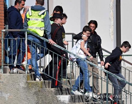 20일 밀라노 인근에서 납치된 뒤 방화로 전소된 스쿨버스에 탑승해 있던 이탈리아 어린이들이 경찰에게 구조된 이후 부모와 함께 귀가하고 있다. [EPA=연합뉴스] 