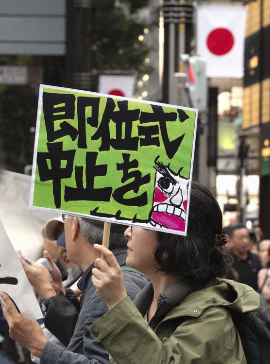 22일 오후 도쿄 도심에서 열린 '천황제' 반대 시위에 참가한 한 시민이 '즉위식 중단'이라고 적힌 손팻말을 들고 있다. 