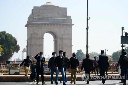 2월 13일 마스크를 쓰고 인도 뉴델리 시내 인디아게이트 앞을 지나는 관광객. [AFP=연합뉴스]