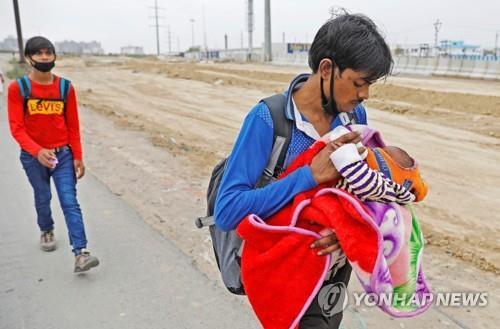 인도에 전국 봉쇄령이 내려져 일자리가 사라지자 아기에게 우유를 주면서 고향으로 걸어서 이동하는 뉴델리 외곽의 떠돌이 근로자. [로이터=연합뉴스]