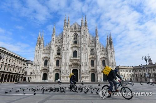 자전거를 타고 이탈리아 밀라노 두오모 광장을 지나는 음식배달업체 직원