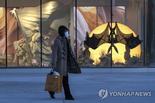 박쥐모양 조형물이 설치된 쇼윈도 옆을 지나가는 베이징 시민