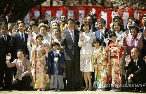 2019년 4월 13일 아베 신조(安倍晋三) 당시 일본 총리가 부인 아키에(昭惠) 여사와 함께 도쿄 공원인 '신주쿠 교엔'에서 열린 '벚꽃을 보는 모임' 행사에서 참석자들과 기념사진을 찍고 있다. [교도=연합뉴스 자료사진]