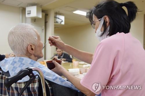 (도쿄 교도=연합뉴스) 일본 도쿄의 한 노인복지시설에서 직원이 고령자의 식사를 돕고 있다.