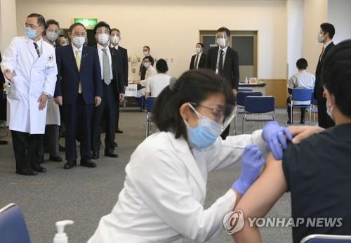 지난 18일 도쿄메디컬센터에서 코로나19 백신 접종 모습을 지켜보고 있는 스가 요시히데(위 왼쪽 2번째) 총리. [AFP=연합뉴스 자료사진]