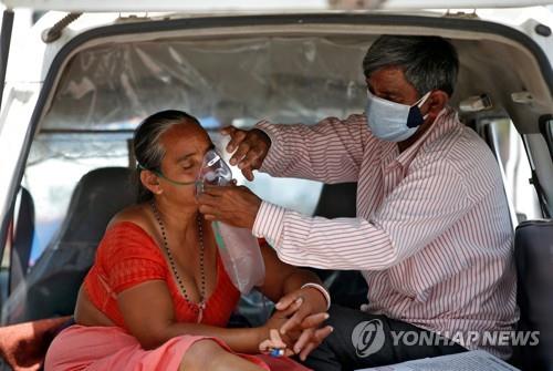 인도 아메다바드의 한 병원 밖 차 안에서 진료를 기다리며 산소 마스크를 손보는 부부. [로이터=연합뉴스]