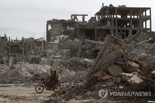 지난달 파괴된 야르무크 캠프의 거리를 스쿠터로 이동하는 시리아군