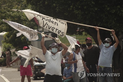 엘살바도르 빈민들이 지나는 차량을 향해 식량 지원을 호소하는 흰 깃발을 흔들고 있다.