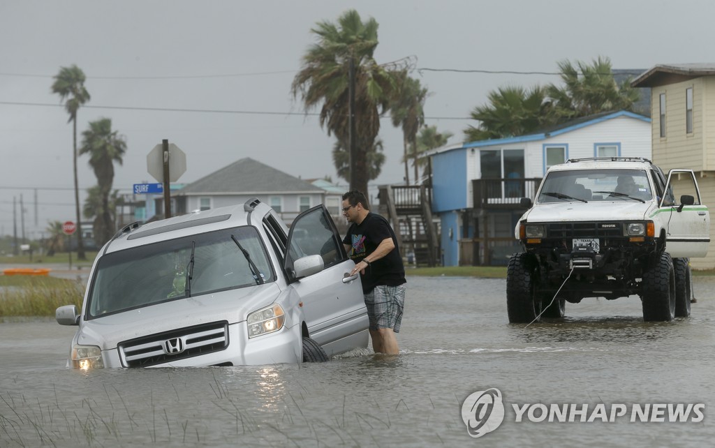 침수된 차량을 물 밖으로 끄집어내려고 시도하는 텍사스주 서프사이드 주민