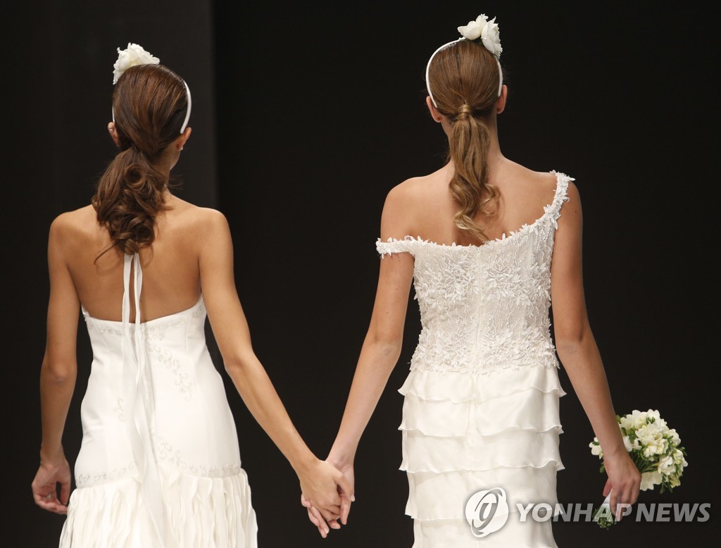 2014년 로마에서 열린 '레인보우 웨딩 패션쇼'에서 두 여성이 손을 맞잡고 워킹을 하는 모습. [AP=연합뉴스]