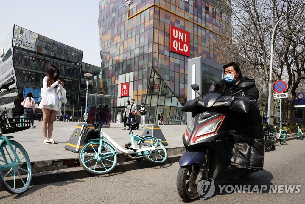 25일 베이징 싼리툰에서 유니클로와 아디다스 매장 앞으로 오토바이가 지나가고 있다. [AP=연합뉴스]