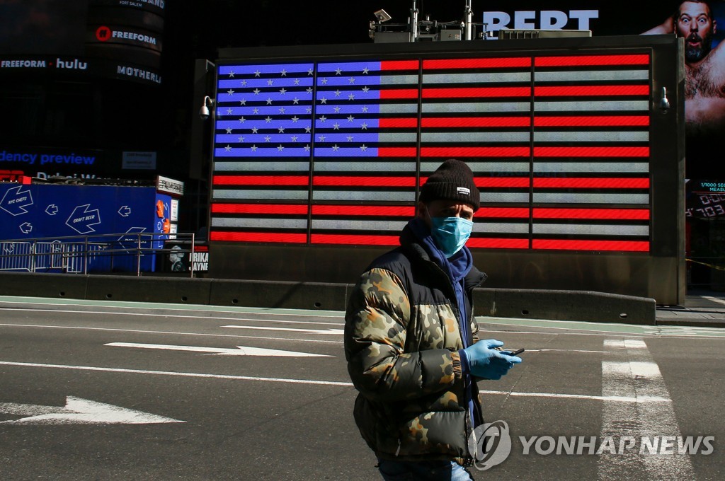 2020년 3월 22일 마스크를 쓴 남성이 미국 뉴욕 타임스 스퀘어를 지나고 있다. [AFP=연합뉴스자료사진]