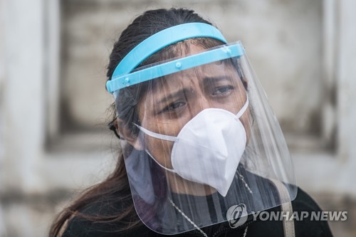 마스크와 얼굴 가리개를 착용하고 친지 장례식에 참석한 페루 여성