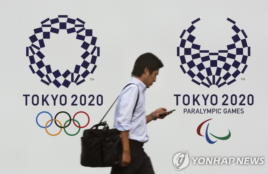 도쿄올림픽 엠블럼 앞을 지나는 시민