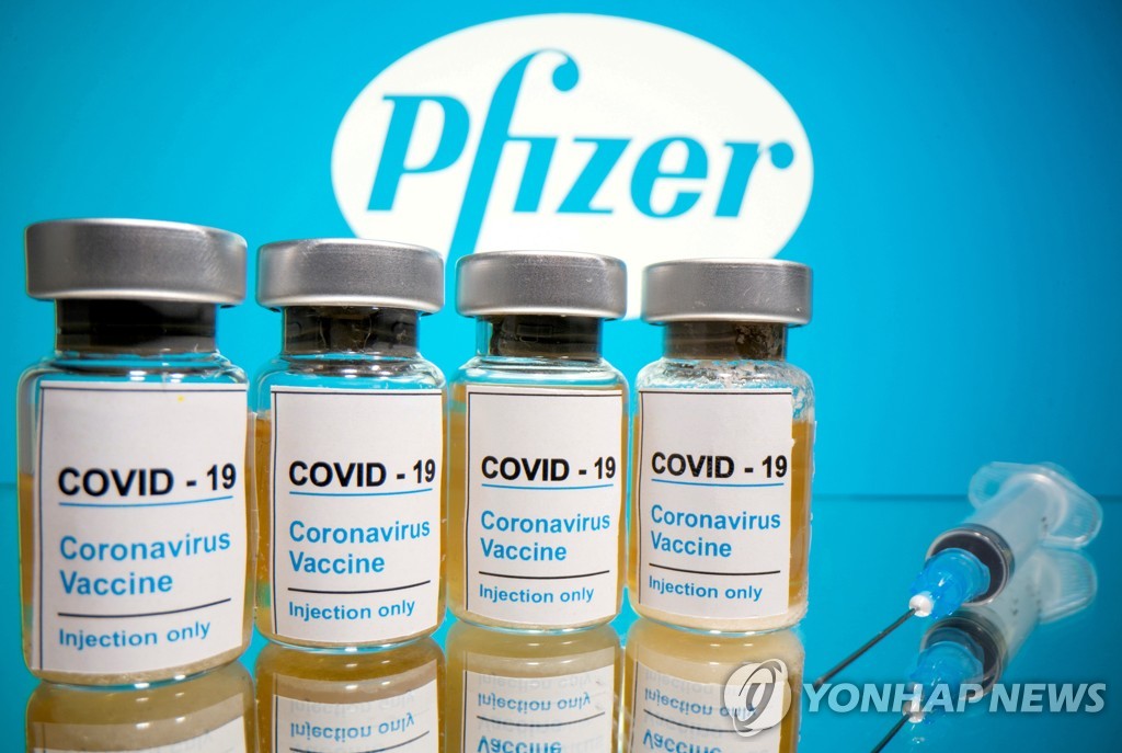 미국 제약사 화이자 로고 앞으로 신종 코로나바이러스 감염증(코로나19) 백신이라고 쓰인 병이 놓여있다. [로이터=연합뉴스 자료사진]