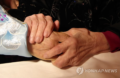 남한에 거주하는 어머니가 북한에 살고 있는 딸의 손을 꼭 잡고 있다.(연합뉴스 자료사진)