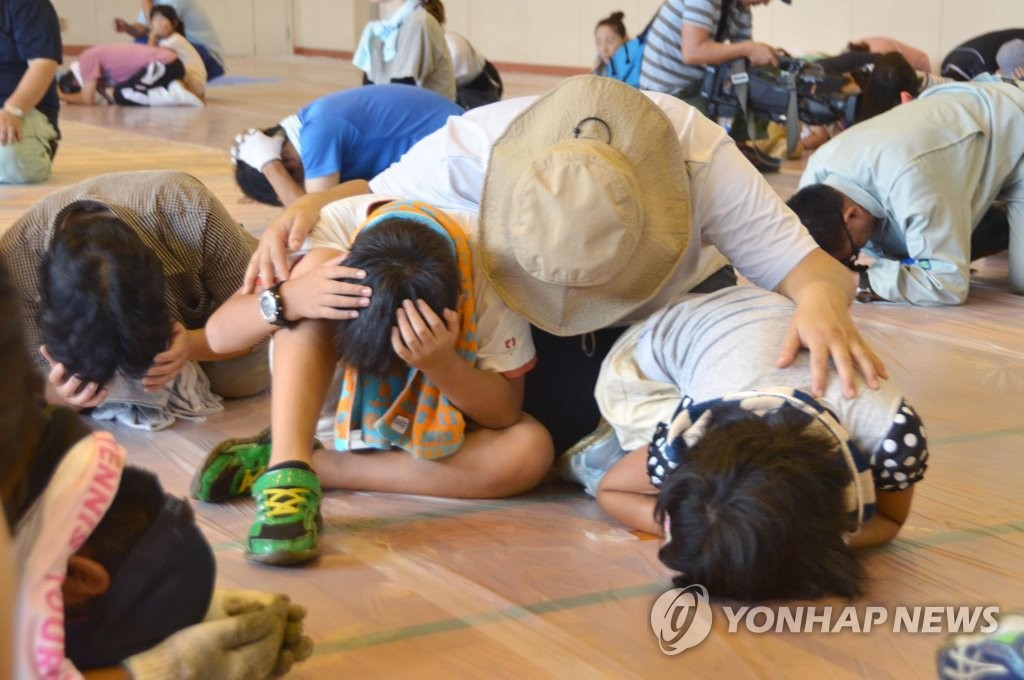 체육관 바닥에 엎드린 일본 주민들