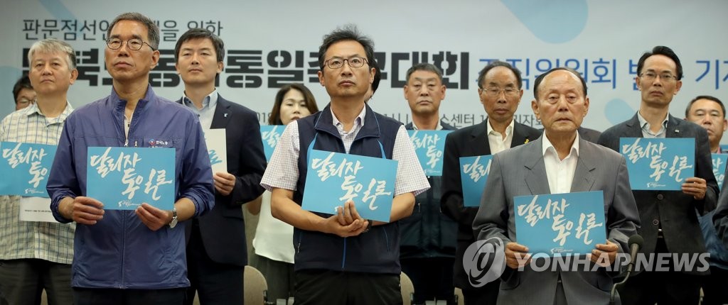韓国労総と民主労総は７月末、サッカー大会に向け組織委員会を発足させた。「走ろう、統一へ」と書かれたカードを手にする両労組関係者ら＝（聯合ニュース）