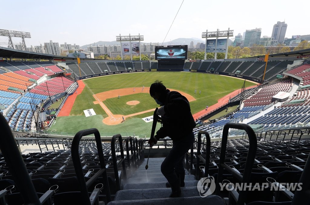 In this file photo from April, 24, 2020, a public health worker sanitizes seats at an empty Jamsil Stadium in Seoul during a Korea Baseball Organization preseason game between the LG Twins and the SK Wyverns. (Yonhap)