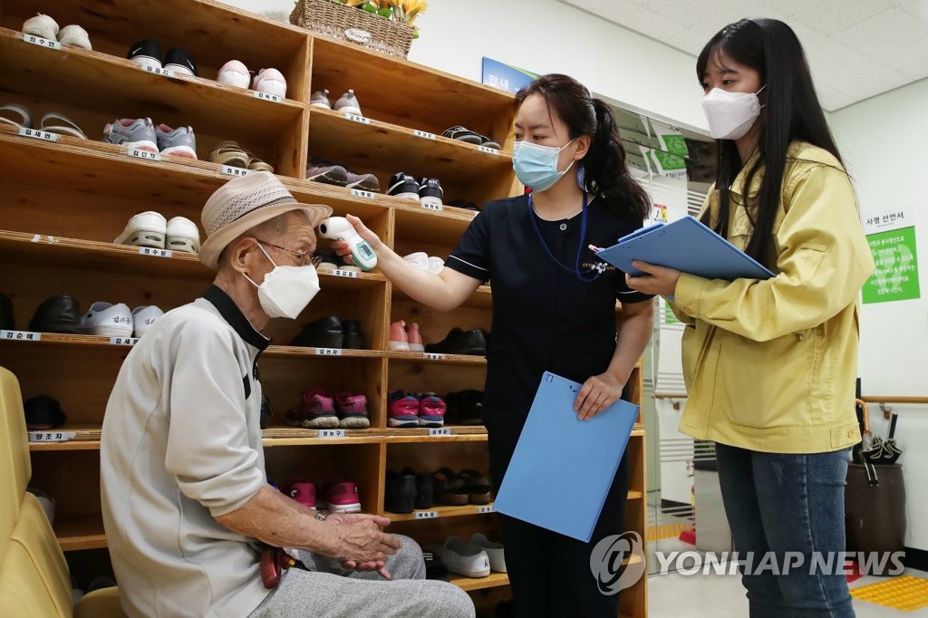This photo, provided by the Seongdong Ward Office on June 12, 2020, shows health workers checking an elderly man's fever at a caregiving facility in the eastern Seoul ward. (Yonhap) (PHOTO NOT FOR SALE)