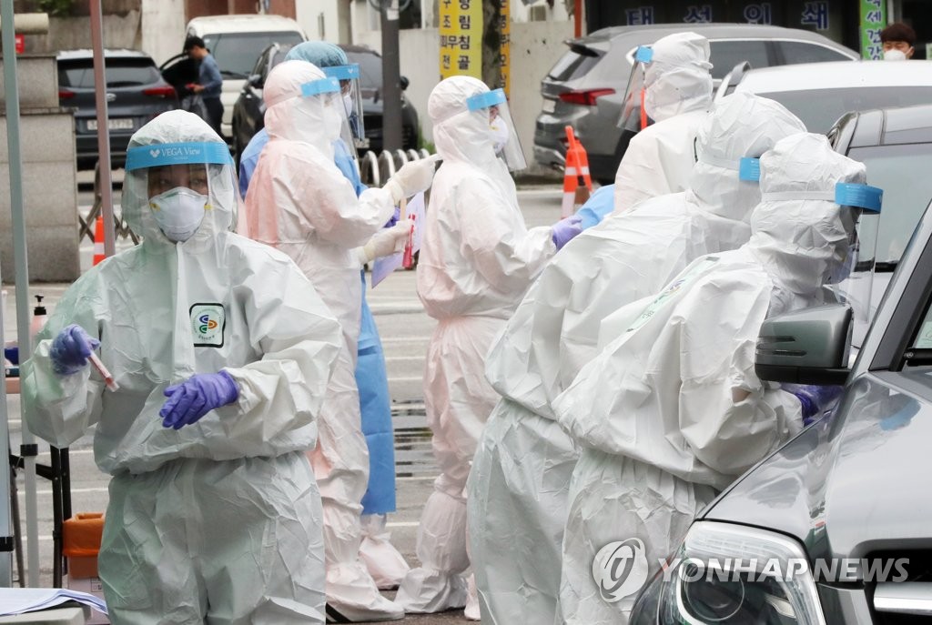 Medical workers gather samples from visitors at a drive-thru checkup center in Gwangju, 330 kilometers south of Seoul, in this file photo taken on July 6, 2020. (Yonhap)