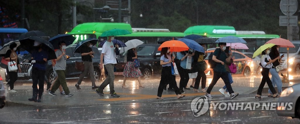 Citizens walk across the Gwanghwamun street in central Seoul on July 23, 2020, as a heavy rain advisory was issued for the capital. (Yonhap)