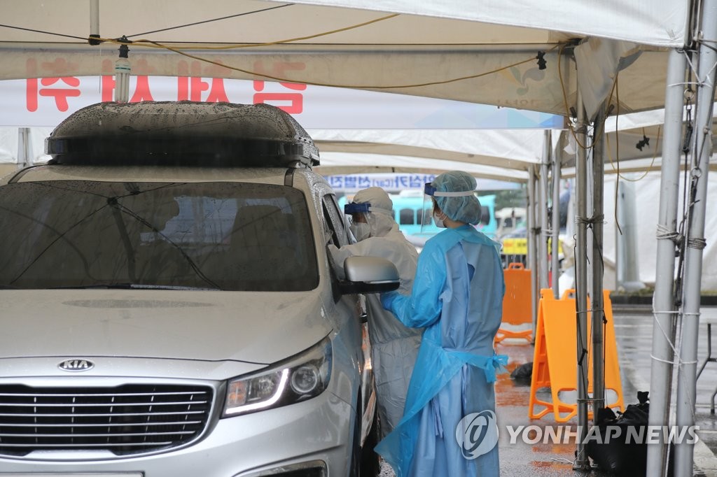 Medical staff members carry out new coronavirus tests at a drive-thru clinic in Goyang, north of Seoul, on Aug. 9, 2020. (Yonhap)